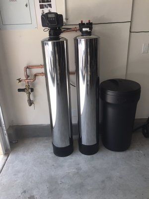 Two water filters are sitting next to each other in a garage.