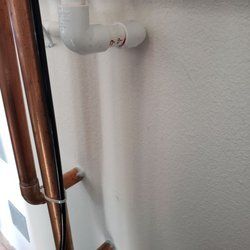 A close up of a copper pipe on a white wall.