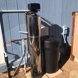 A water softener is sitting outside of a house next to a blue wall.
