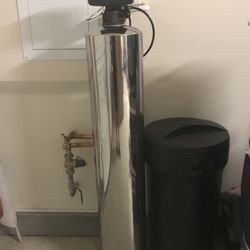 A water softener is sitting in a room next to a wall.