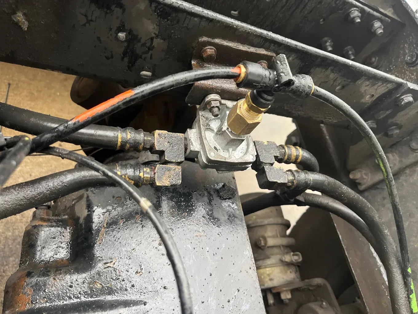 Close-up of truck components, showing interconnected hoses, fittings, and a valve on a black surface.