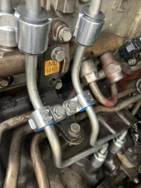 Close-up of a vehicle's engine components, including fuel lines and support bracket.