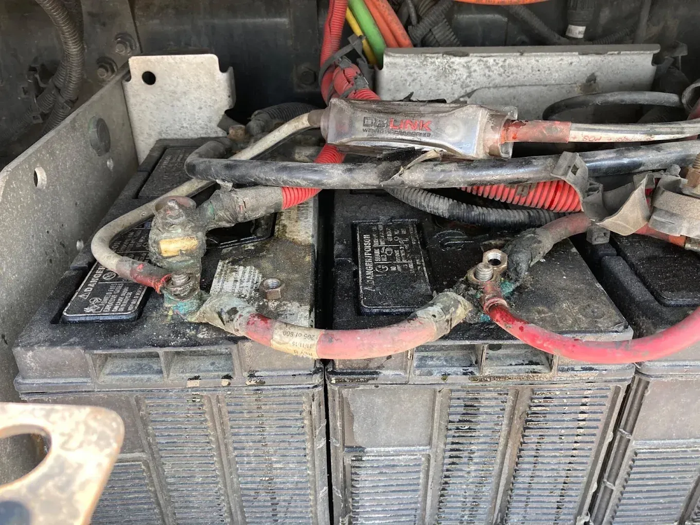 Two vehicle batteries connected by wires, with some corrosion present.