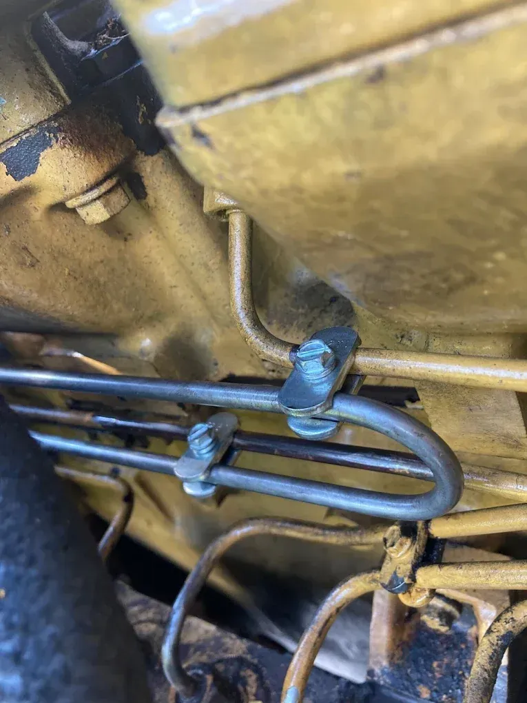 Yellow engine components with metal lines and clips, close-up view.