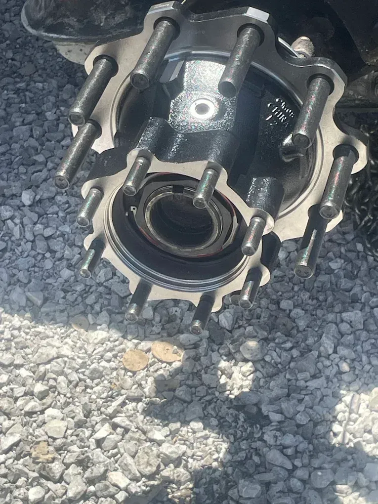 Close-up of a truck wheel hub with lug studs. The hub is black, surrounded by a metal flange.