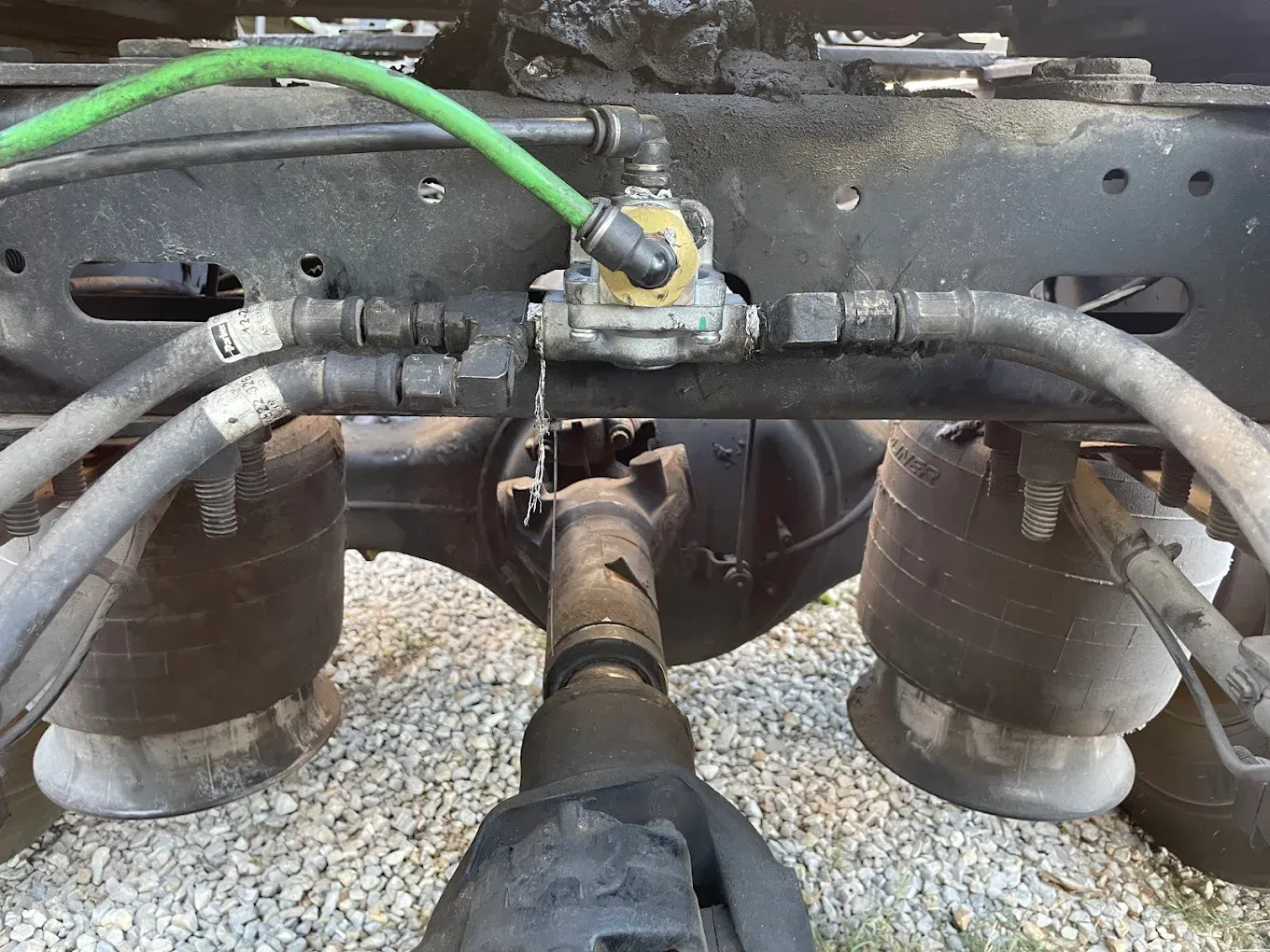 Undercarriage of a truck showing air suspension components, air lines, and a differential.