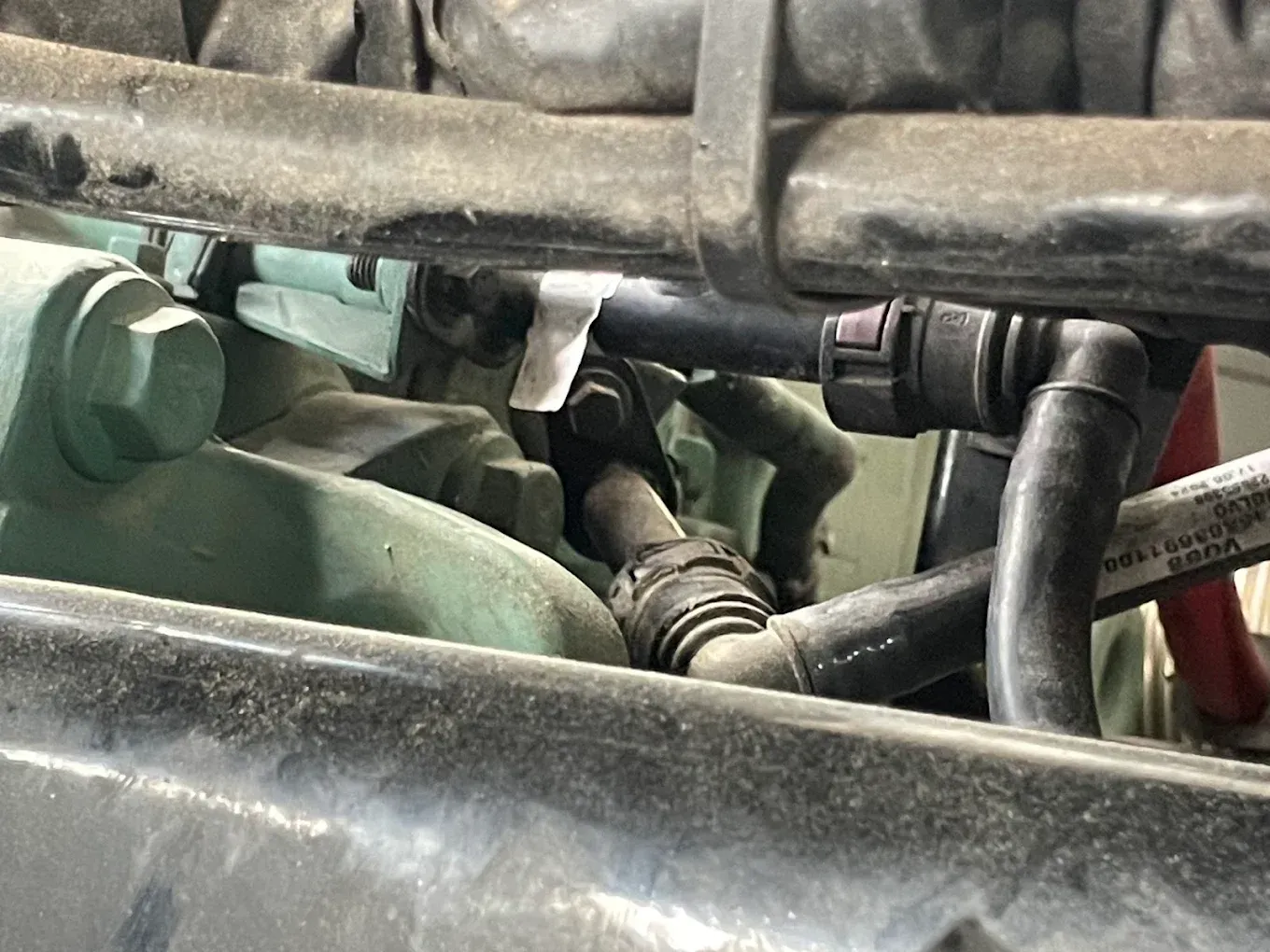 Engine components with various tubes and hoses, primarily black, and a connector.