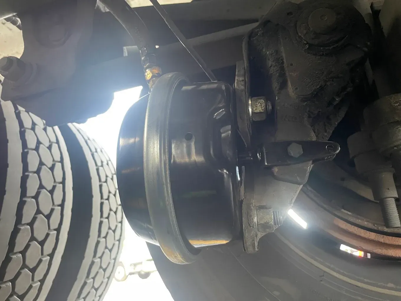 Black brake chamber on a vehicle wheel, with tire visible.