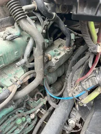 Engine components with hoses, wires, and a valve cluster, likely in a vehicle.