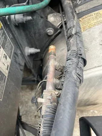 Car engine compartment showing copper AC lines and black hoses.