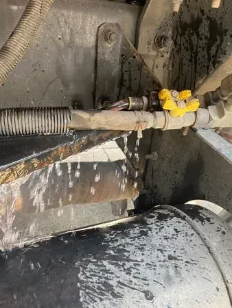 Water leaking from a pipe on machinery; yellow valve visible.