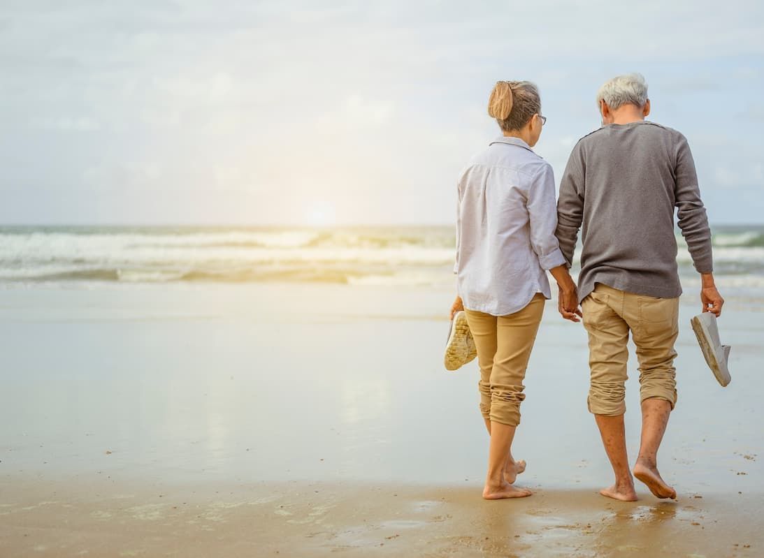 a man and woman walking on the beach holding hands
