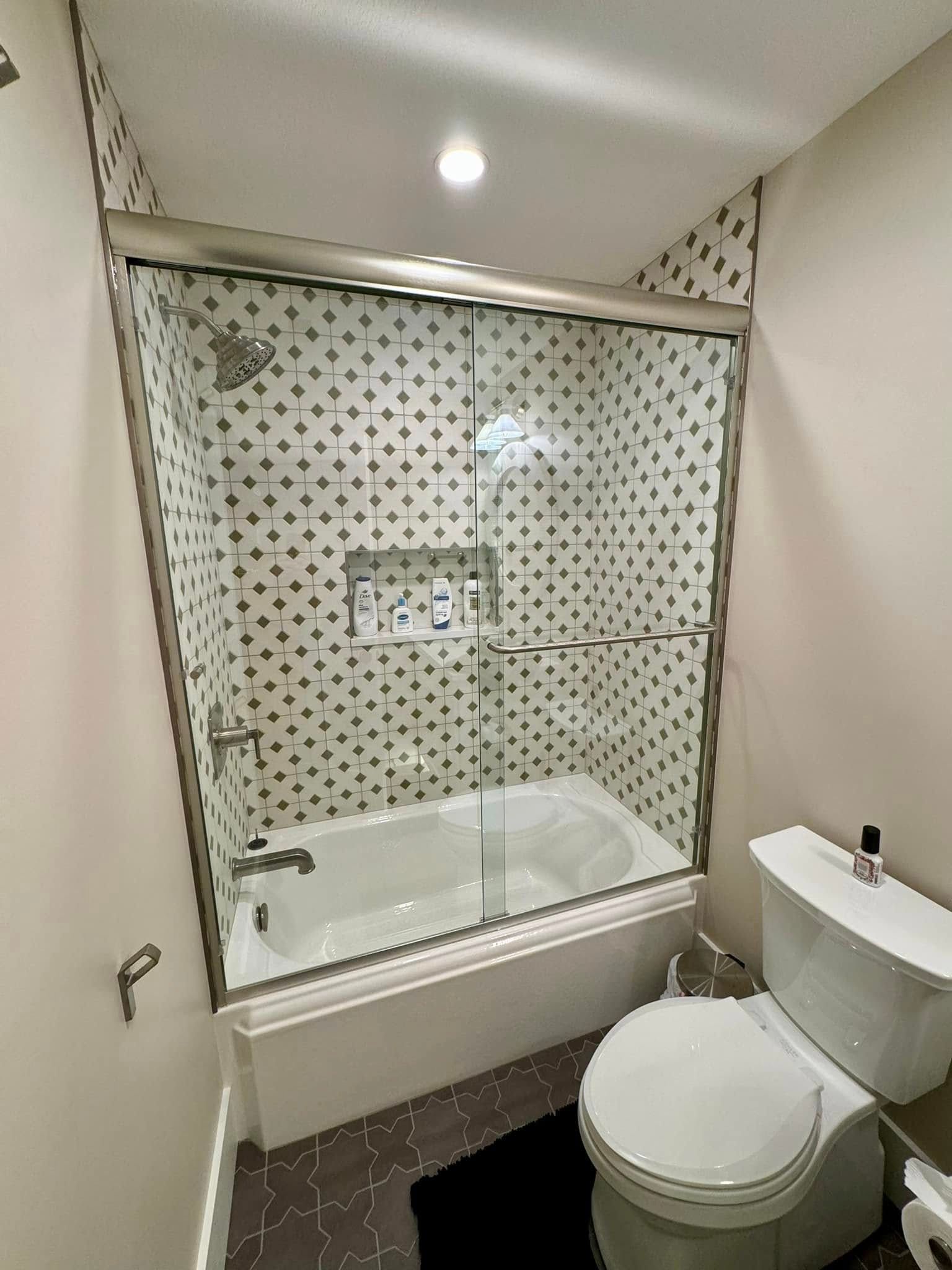 Bathroom with shower, toilet, and decorative tile walls.