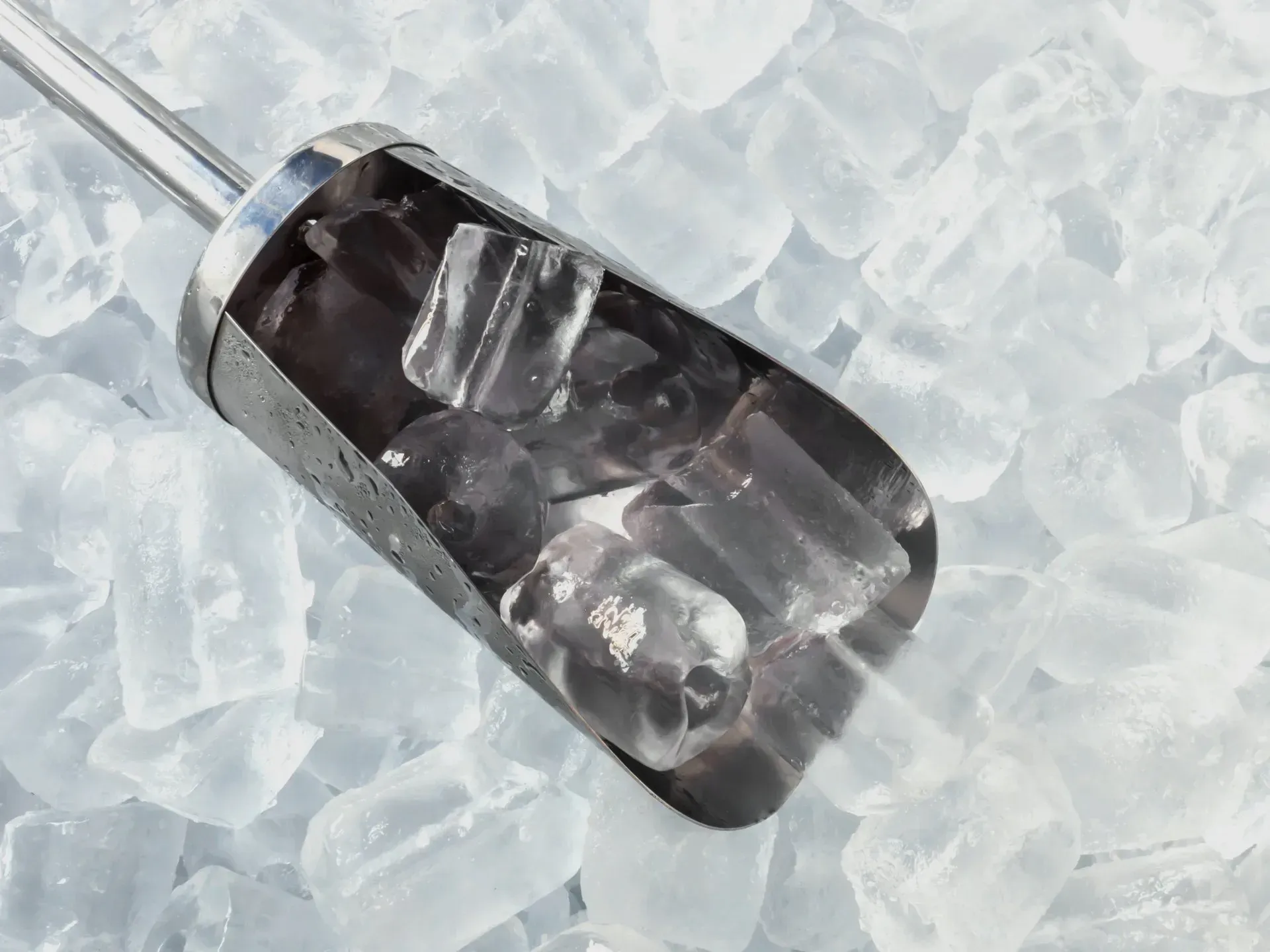 Ice scoop filled with ice cubes sitting on a bed of ice.