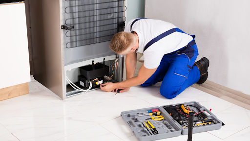 Technician performing refrigerator repair fresno ca service for Bauman's Appliance & Air Conditionin