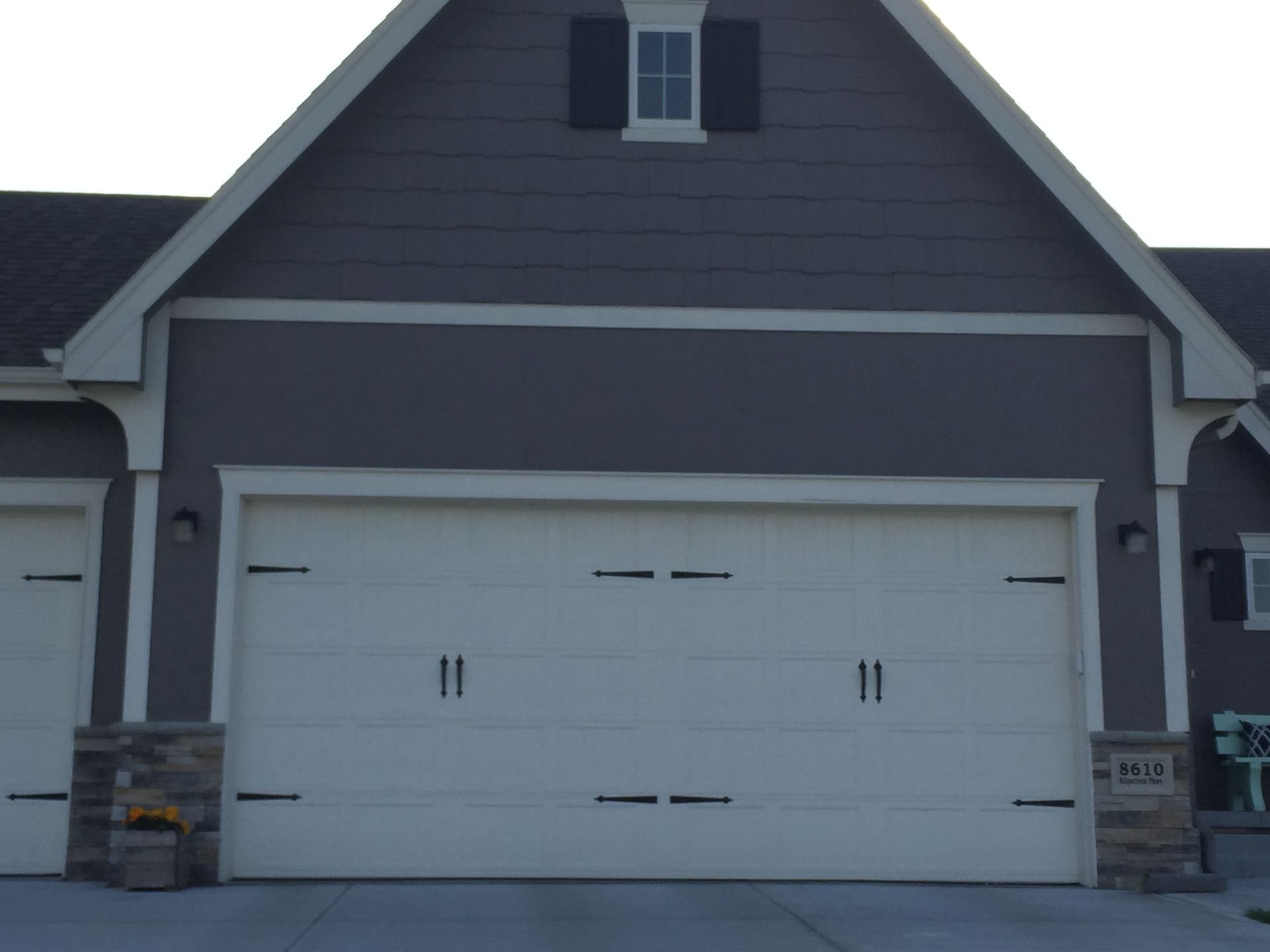 Two-car garage with white doors on a dark gray house exterior
