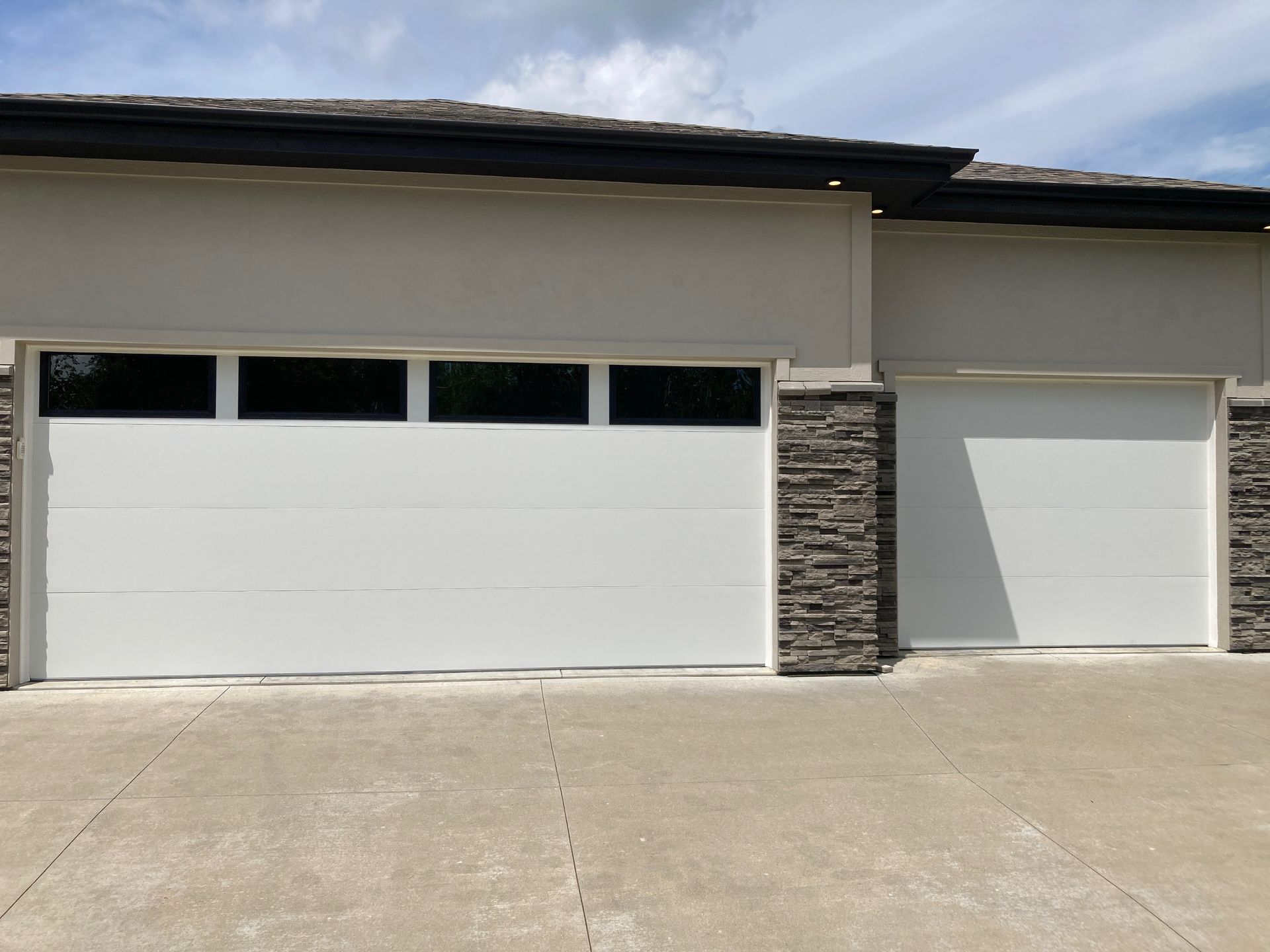 Modern home exterior with two white garage doors and a concrete driveway