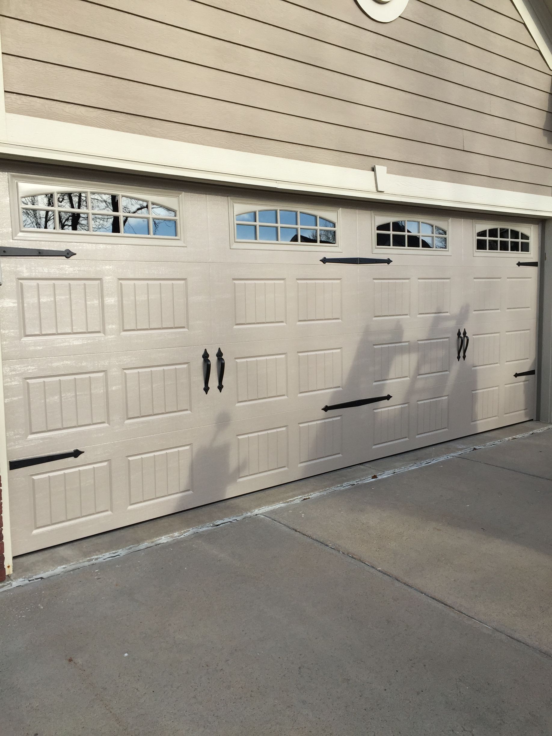 White garage-style double doors on a building, with chipped paint and black handles.