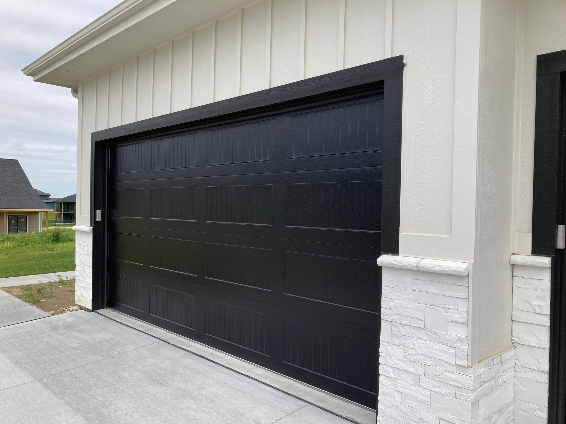 Black garage door on a white house exterior with a driveway in front