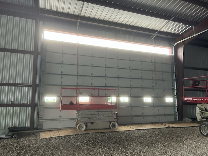Empty warehouse bay with a red scissor lift in front of a large overhead door