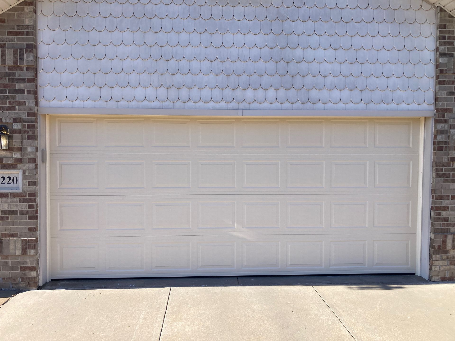 White garage door on a brick building with a small address plaque on the left.