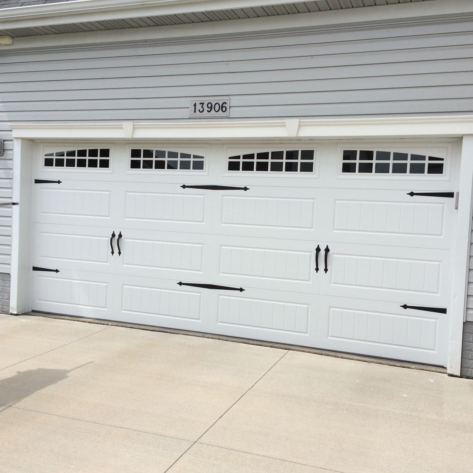 White three-car garage door on a suburban house with the number 13906 above it.