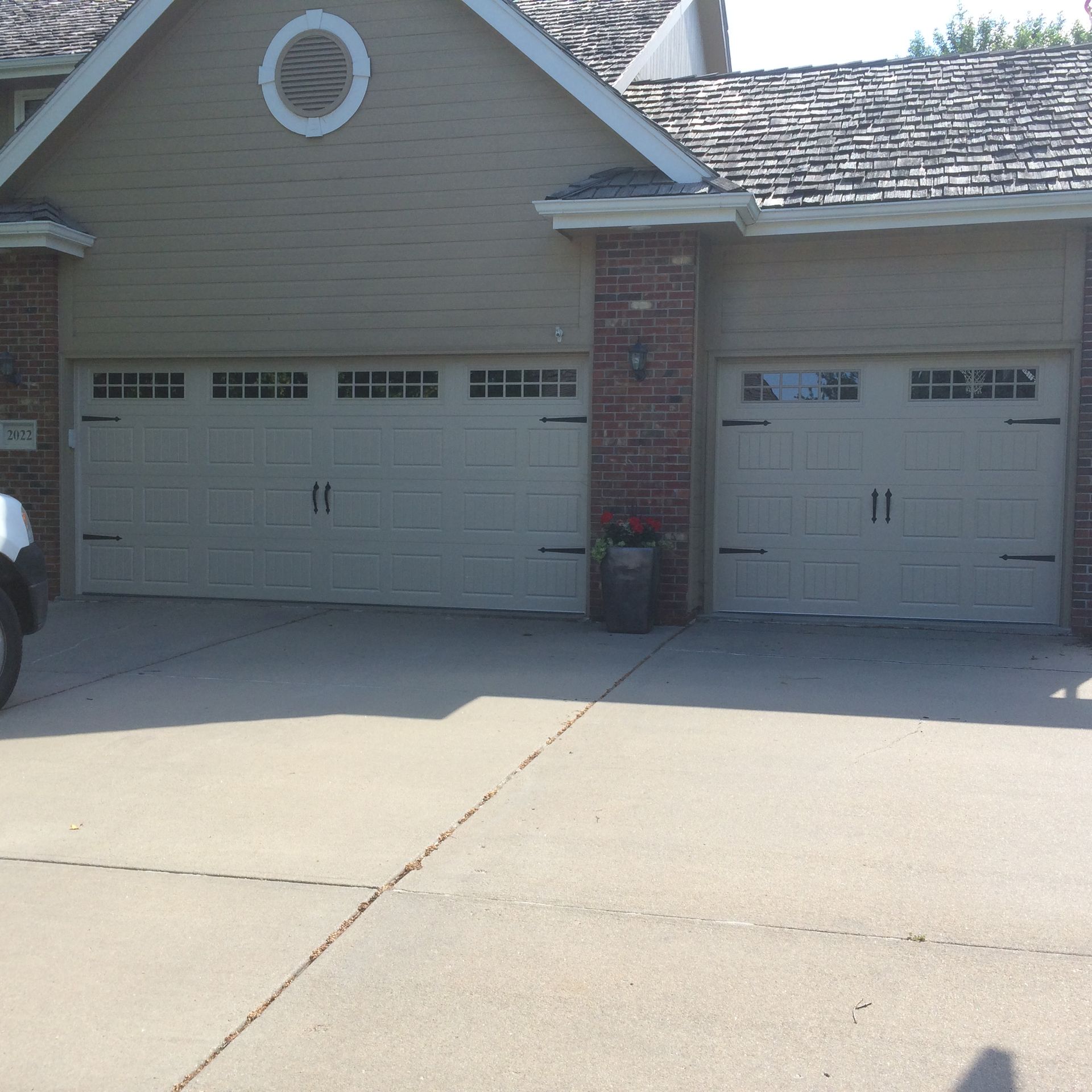 House exterior with two white garage doors, brick accents, and a large concrete driveway