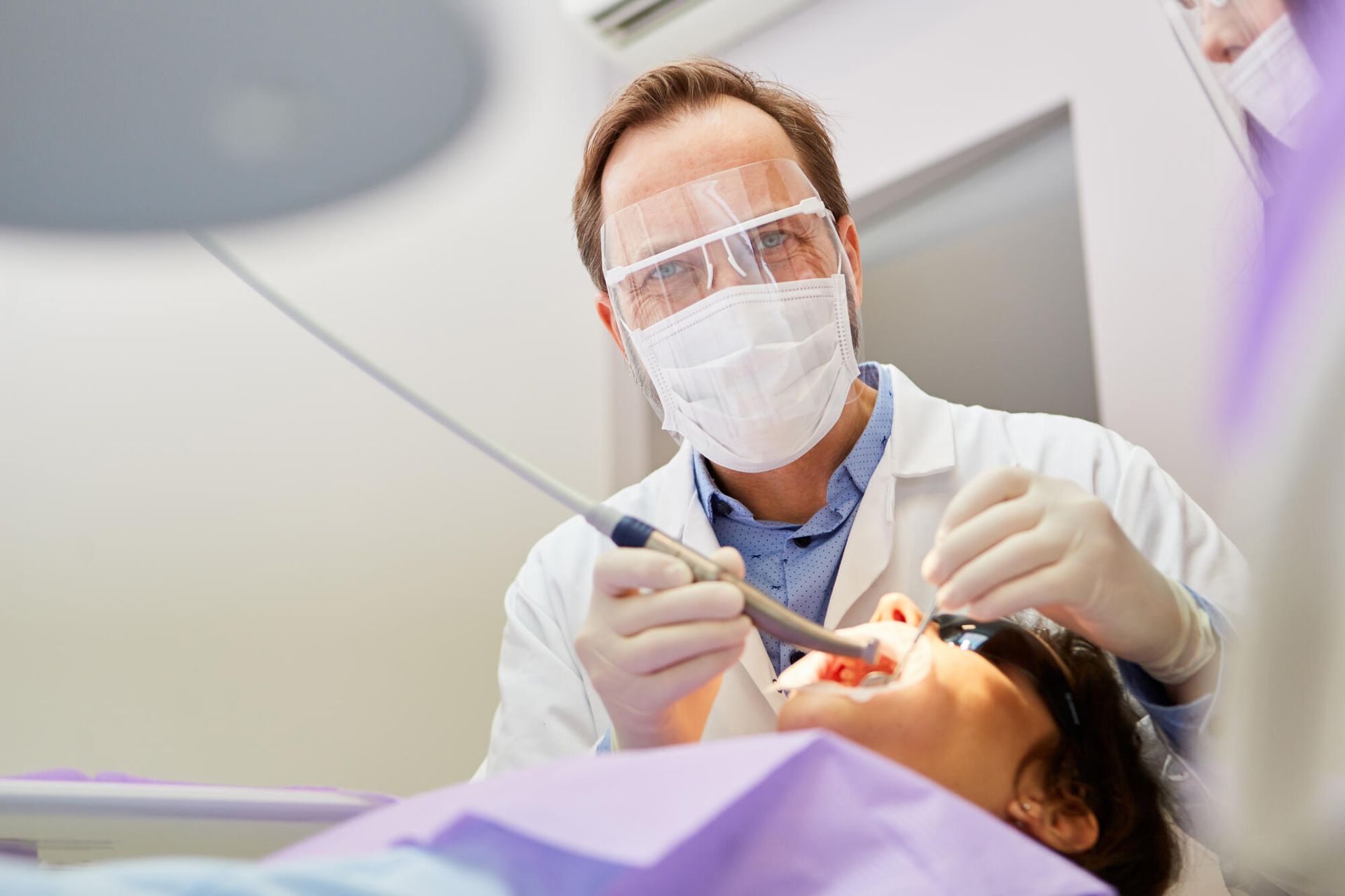 A dentist is examining a patient 's teeth in a dental office.