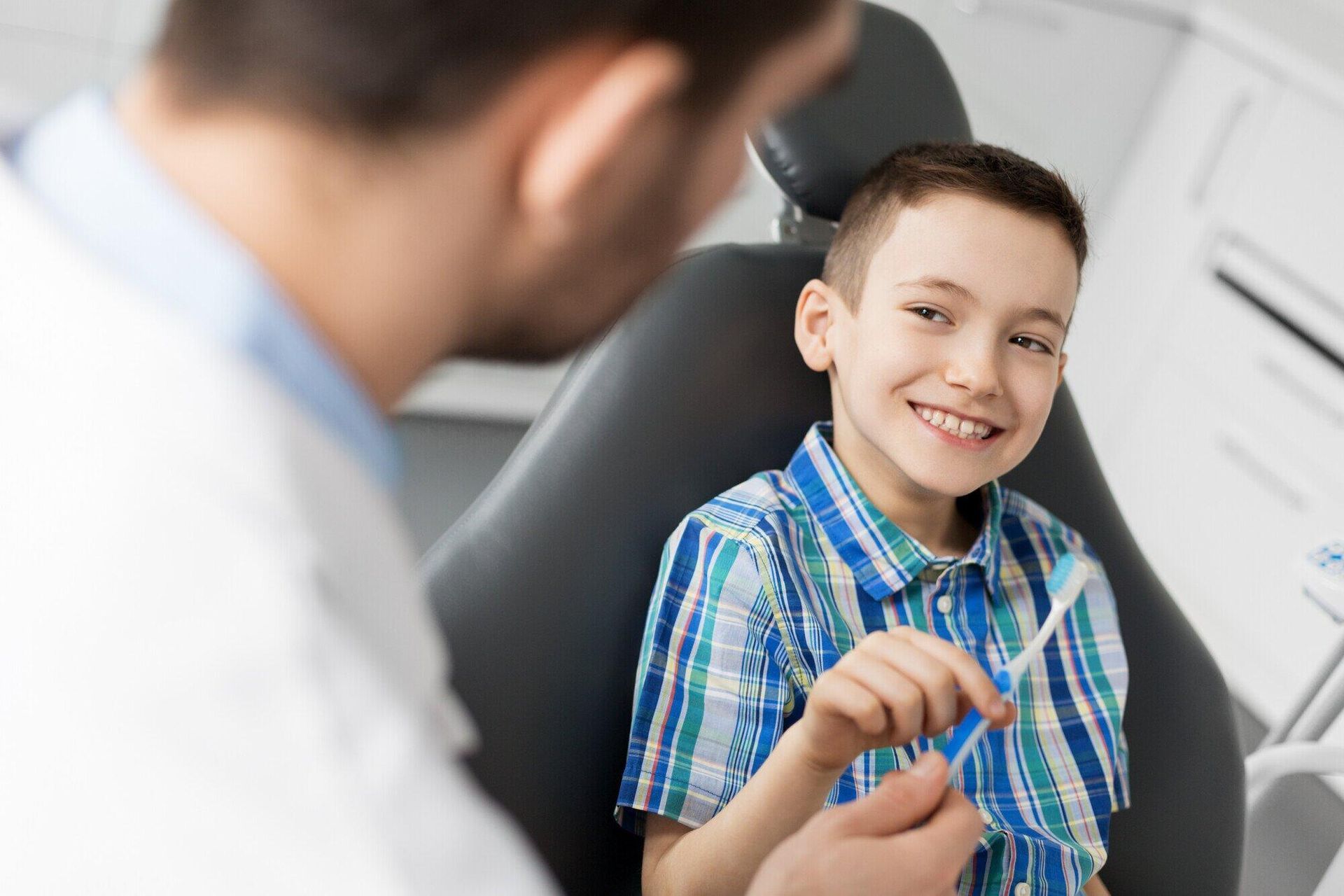 A young boy is sitting in a dental chair talking to a dentist.