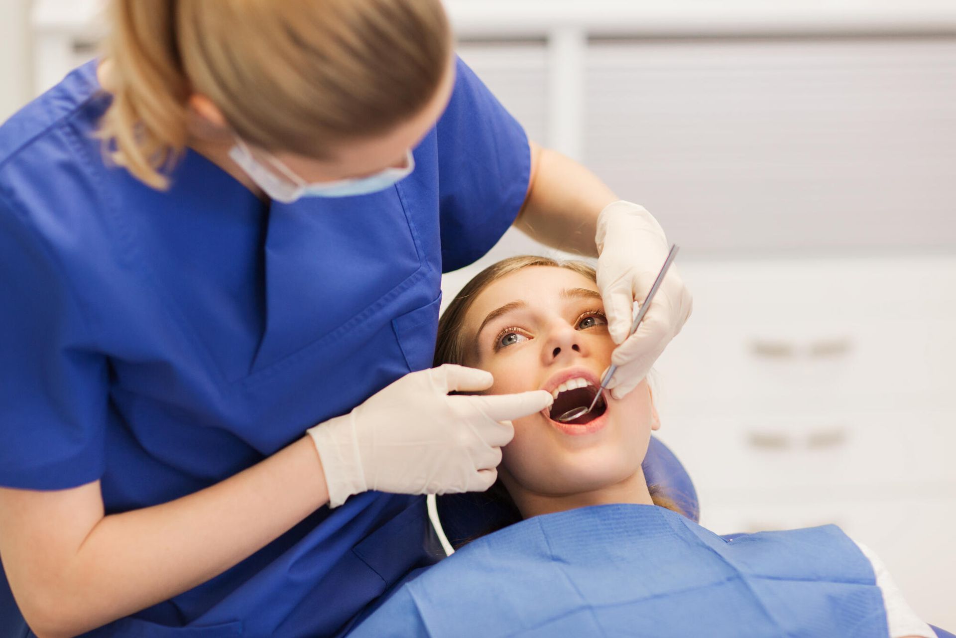 A woman is getting her teeth examined by a dentist.