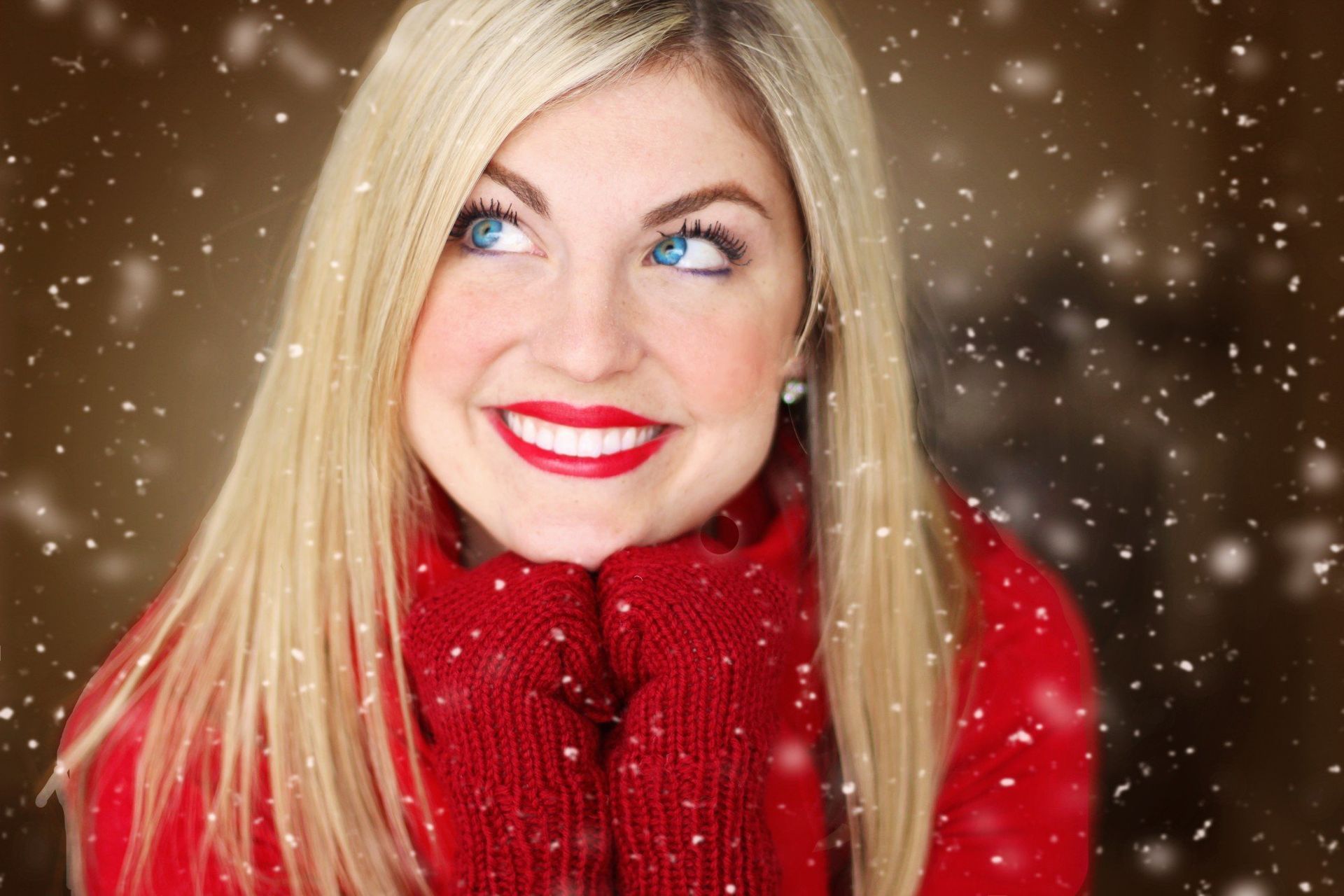 a woman wearing red gloves and a red sweater smiles in the snow