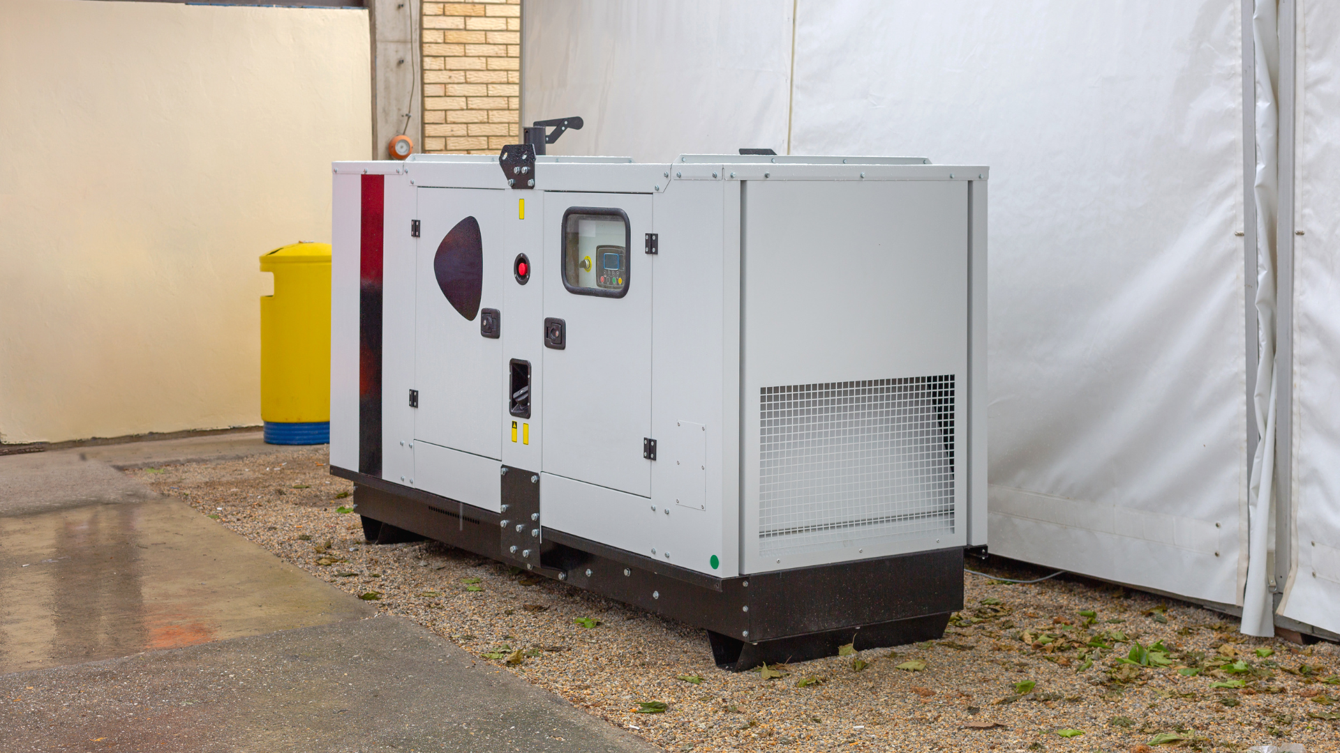 A large white generator is sitting outside of a building.