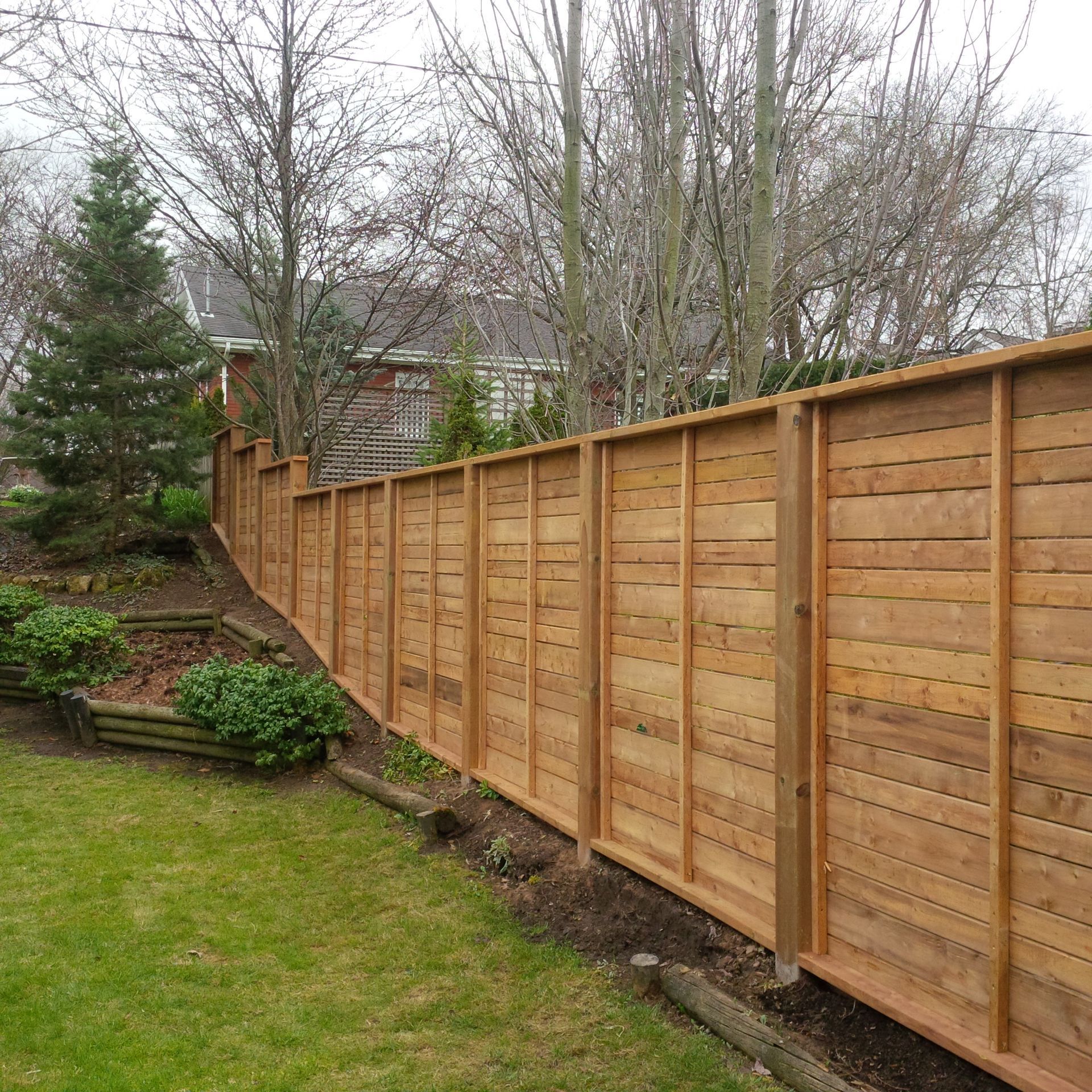 A wooden fence in a backyard with trees in the background