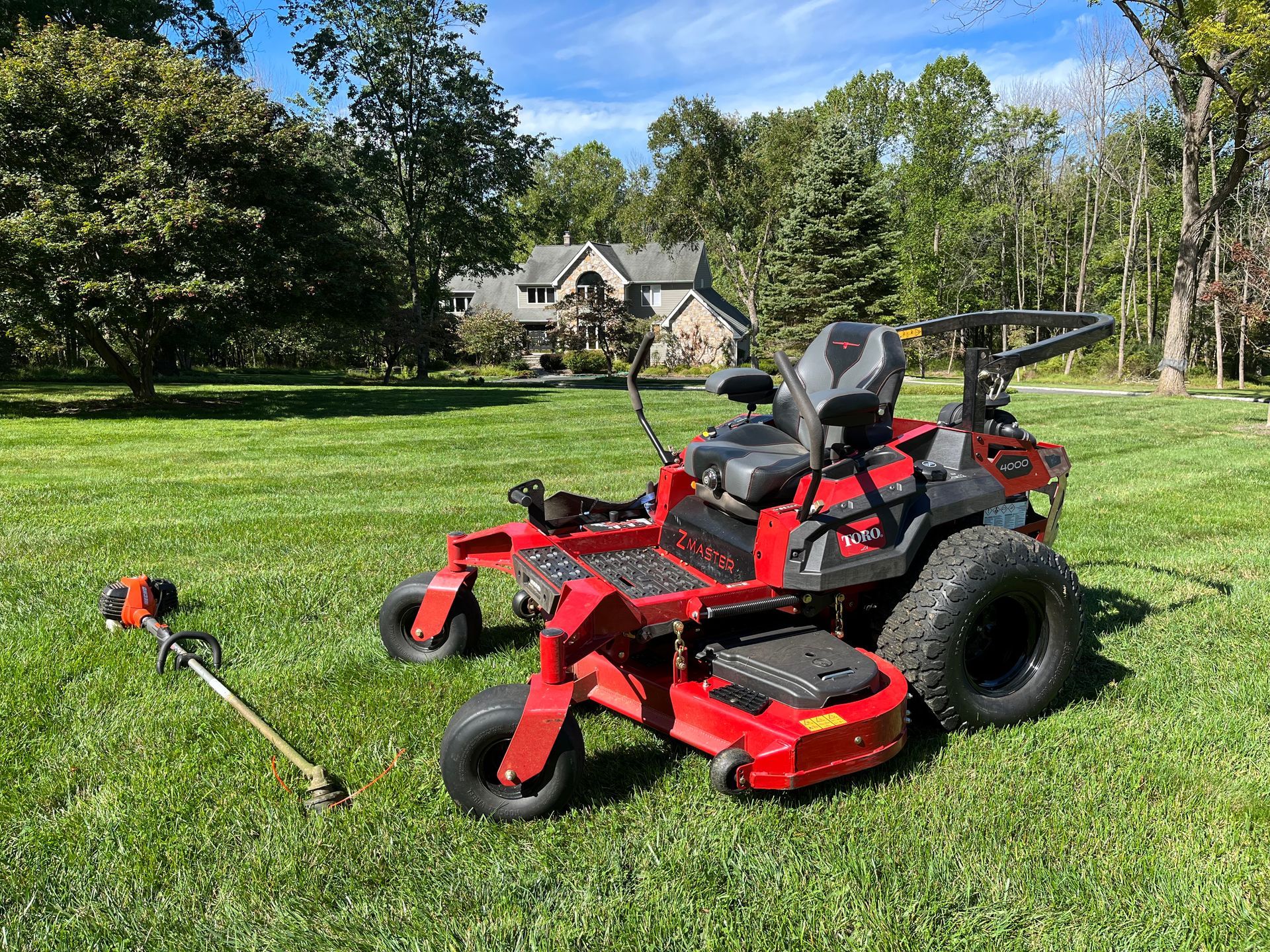 A red lawn mower and a trimmer are sitting on top of a lush green lawn.