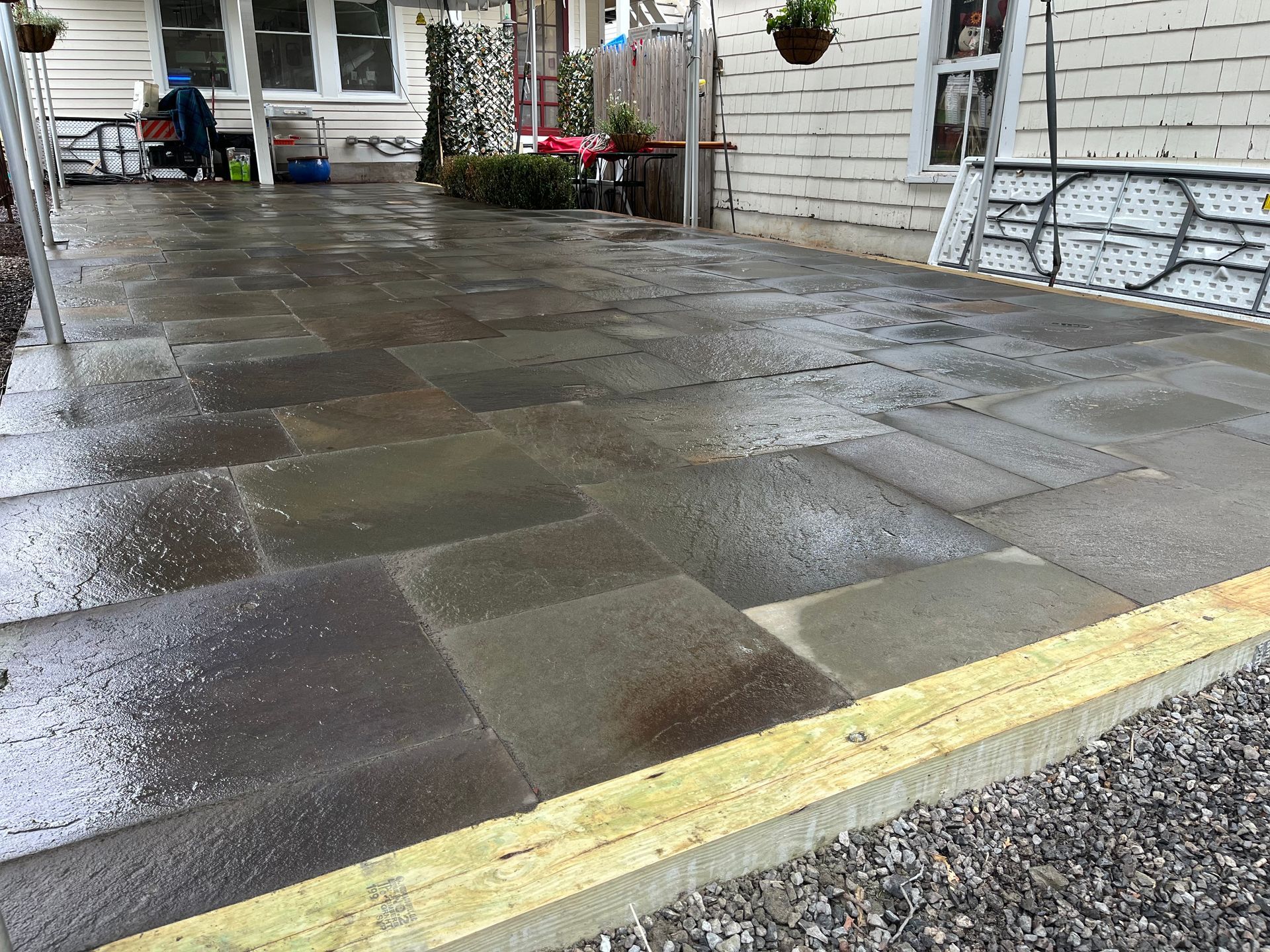 A patio with a yellow border and a white house in the background.