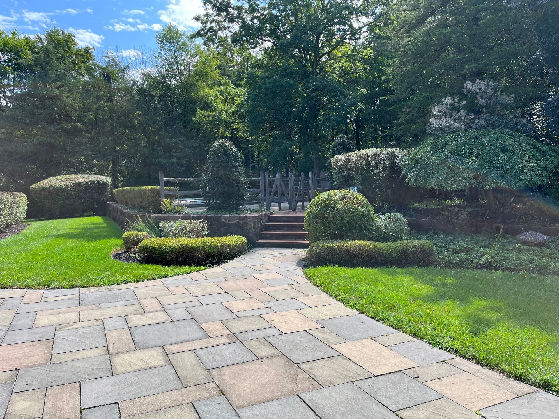 A brick walkway leading to a gate in a garden