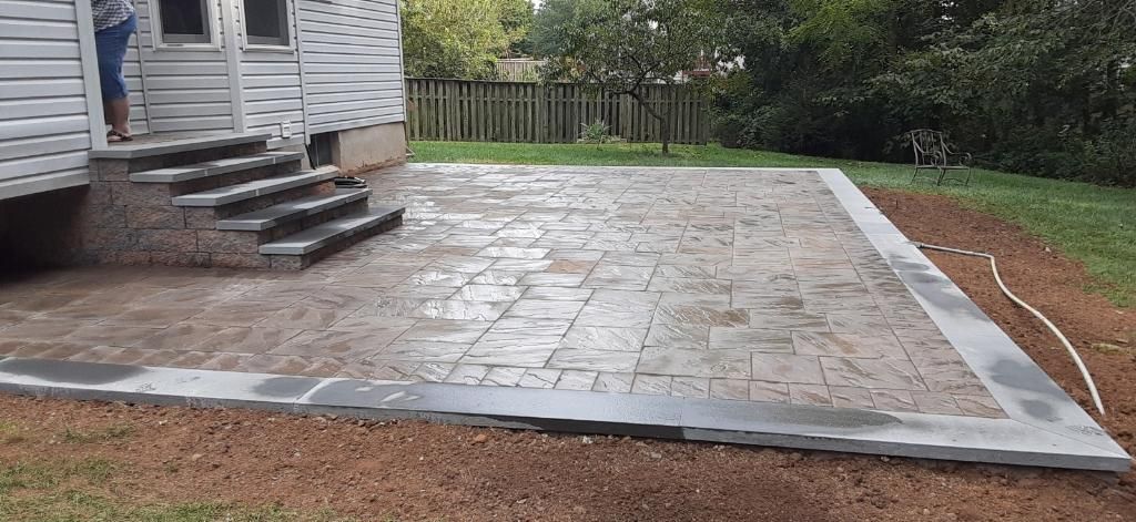 A woman is standing in the doorway of a house next to a concrete patio.