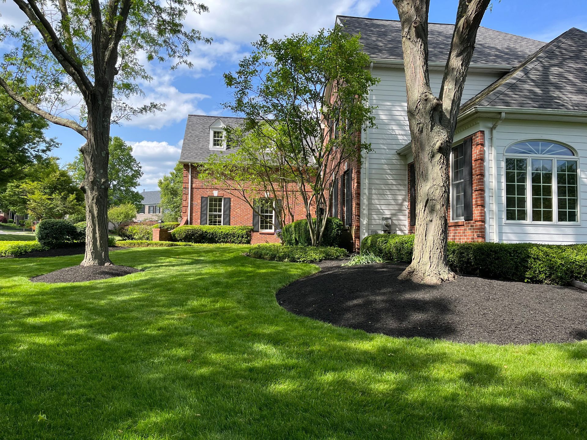 A large brick house with a large lawn in front of it.