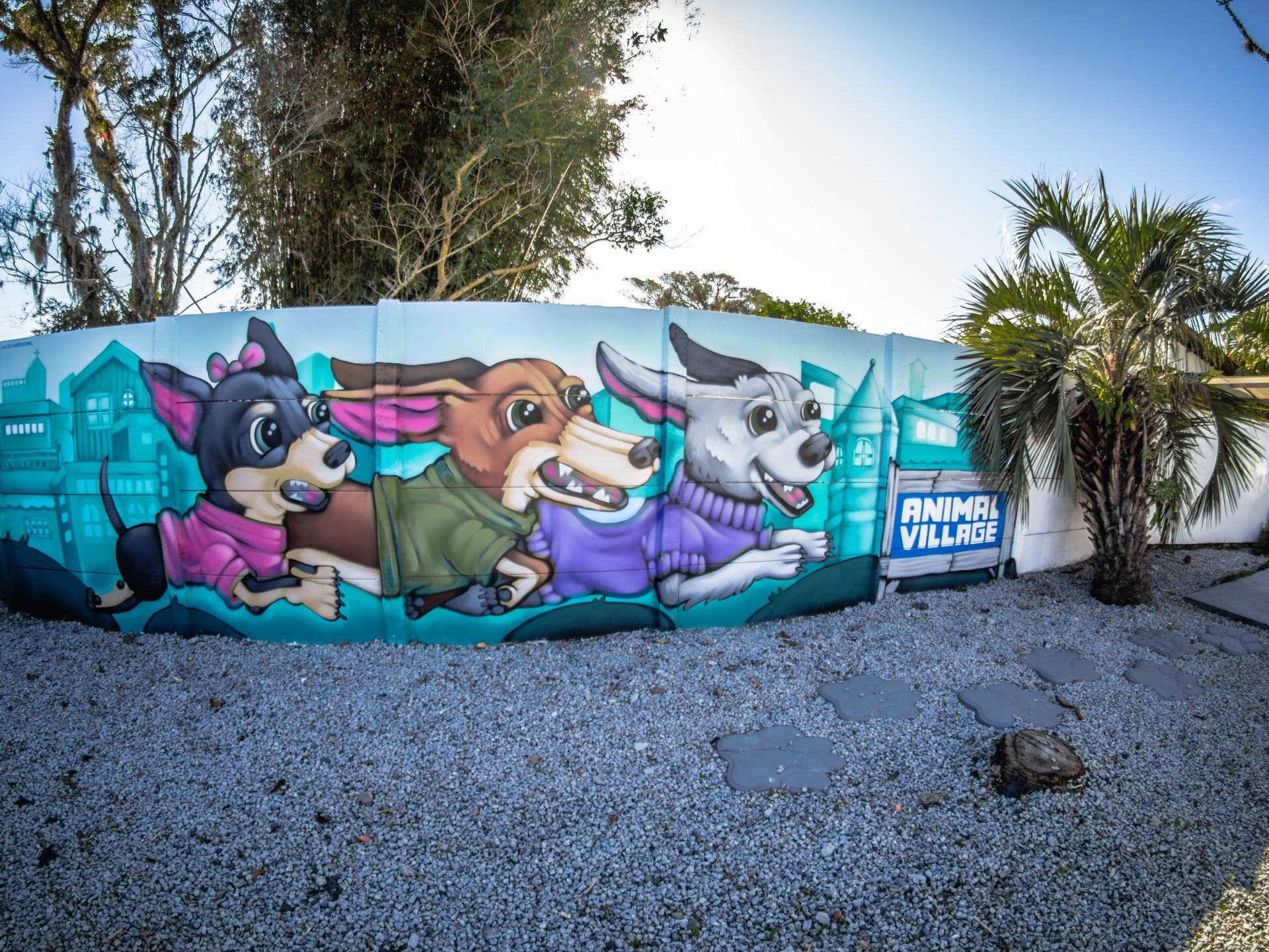 Um mural de três cães vestindo suéteres em uma cerca.