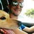 Um homem usando óculos escuros segura um cachorro no colo