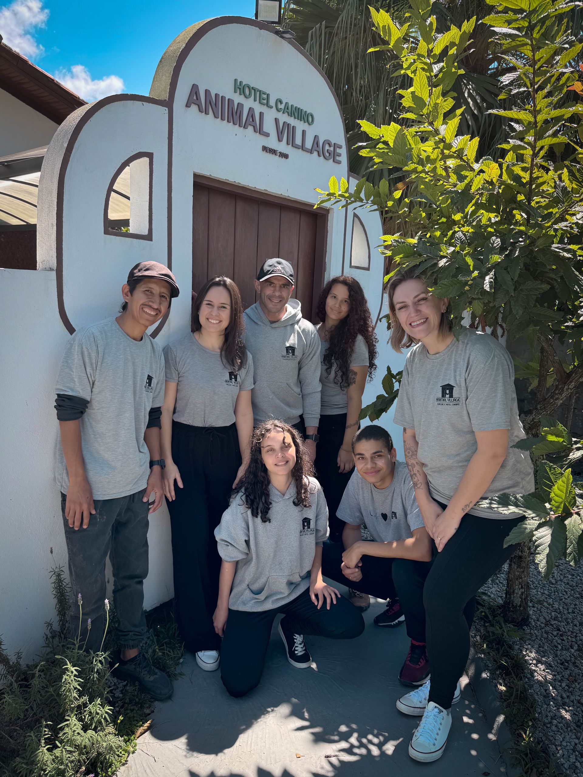 Um grupo de pessoas está posando para uma foto em frente a um prédio que diz