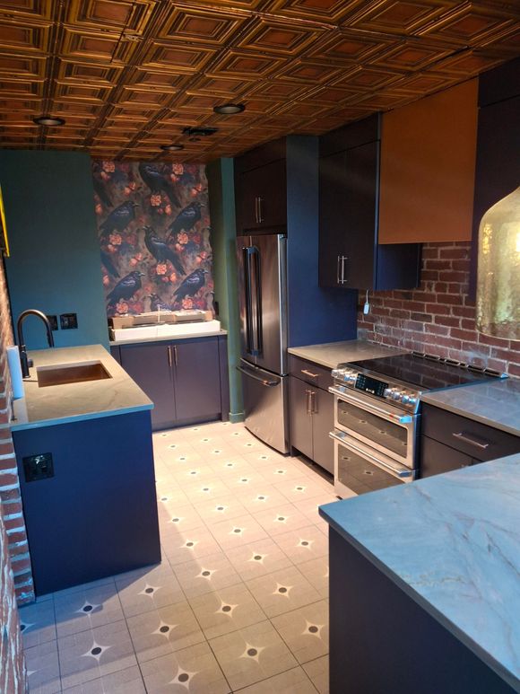 A kitchen with stainless steel appliances and a brick wall