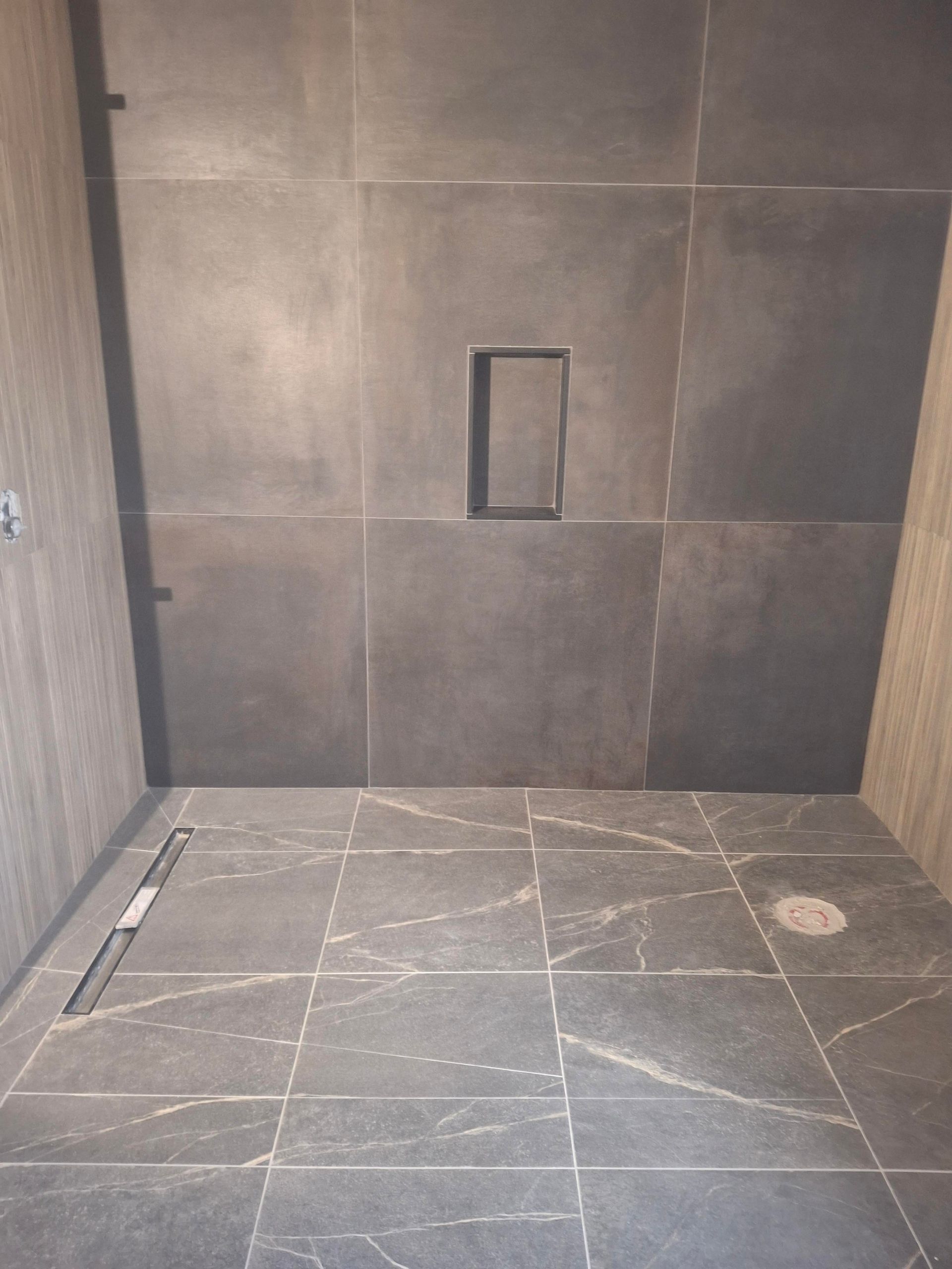 A bathroom with a walk in shower and a tiled floor.