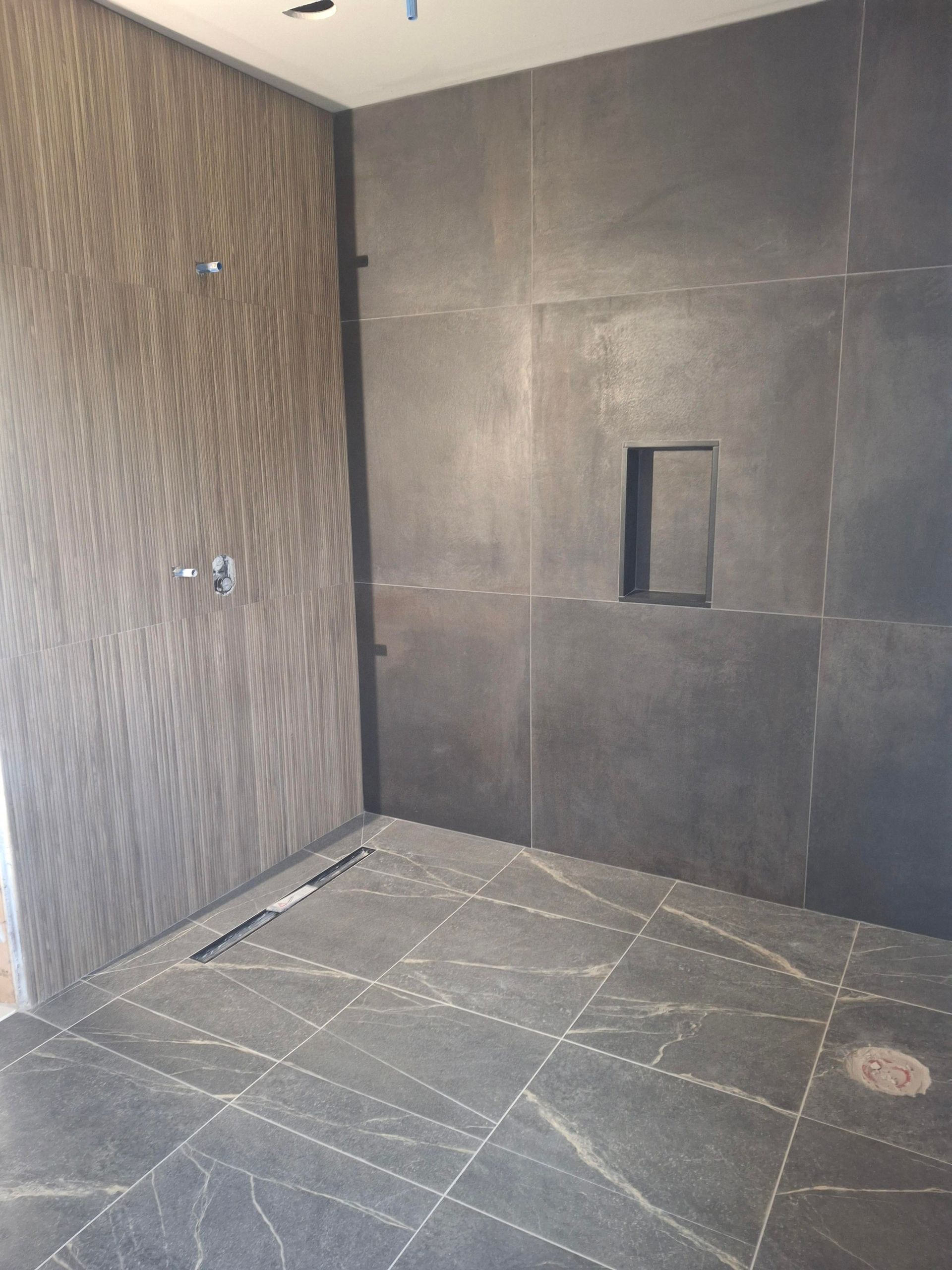 A bathroom with a walk in shower and a tiled floor.