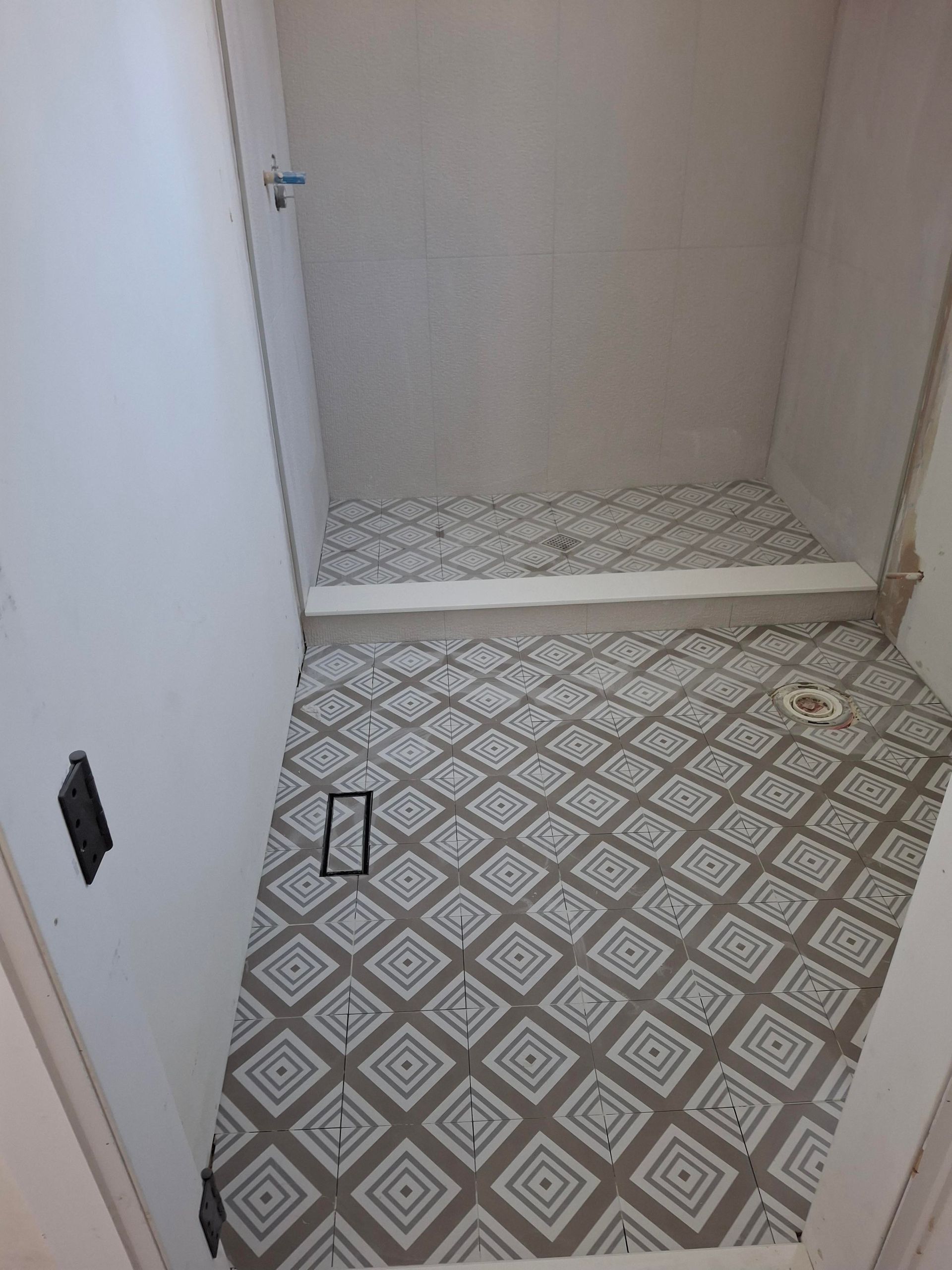 A bathroom with a tiled floor and a shower stall.