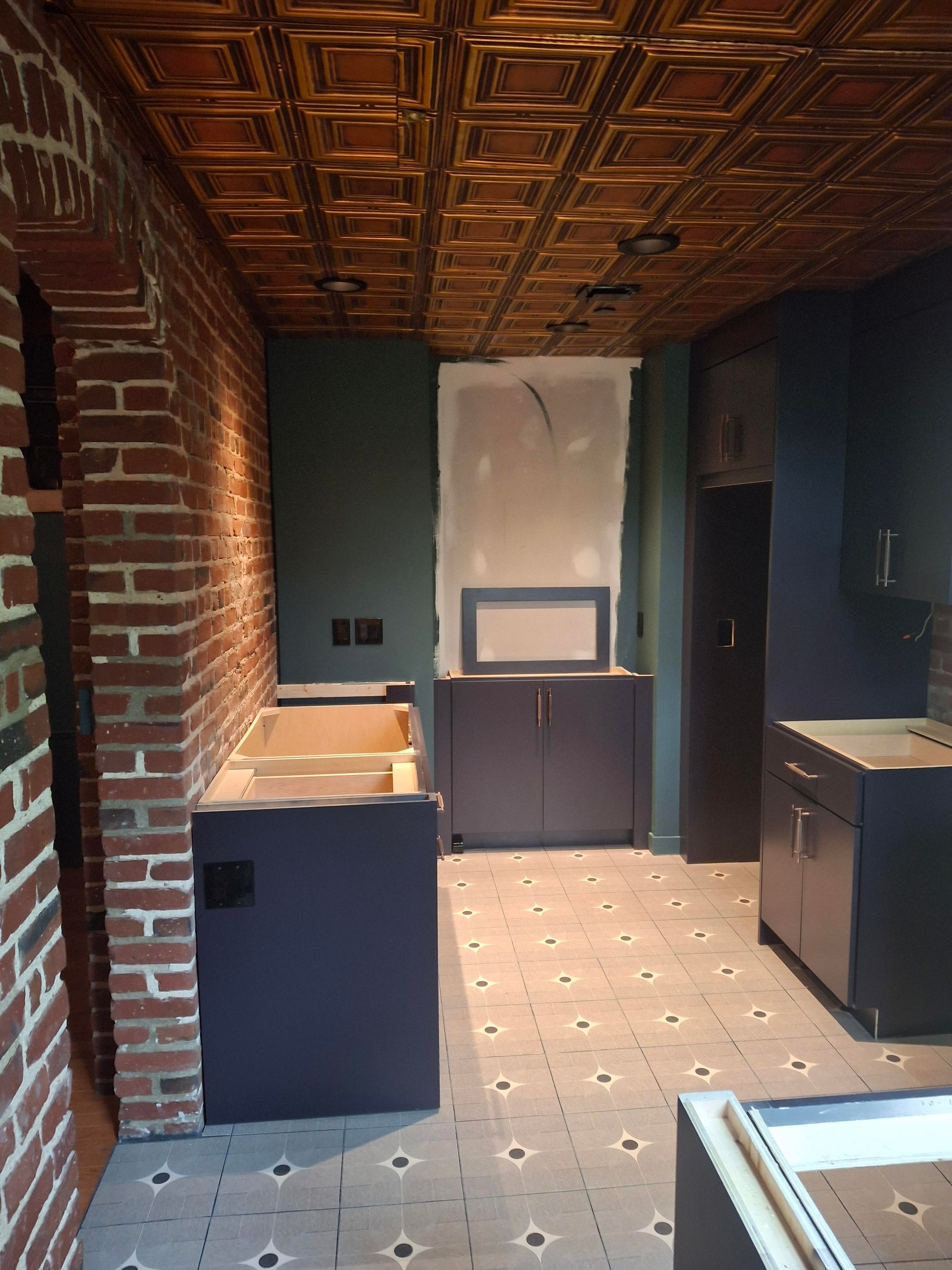 A kitchen with a brick wall and a tiled floor