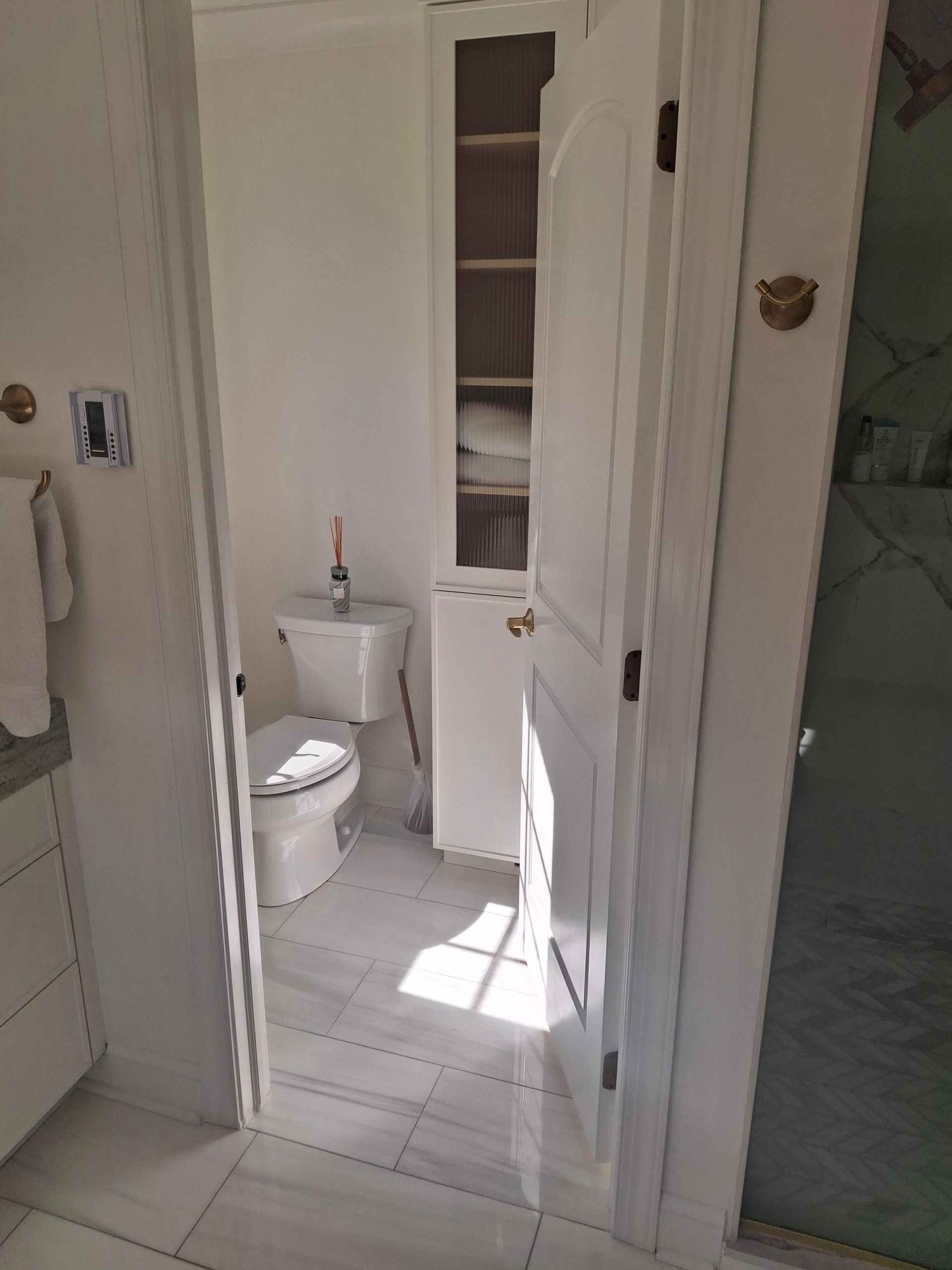 A bathroom with a toilet , sink and cabinets.