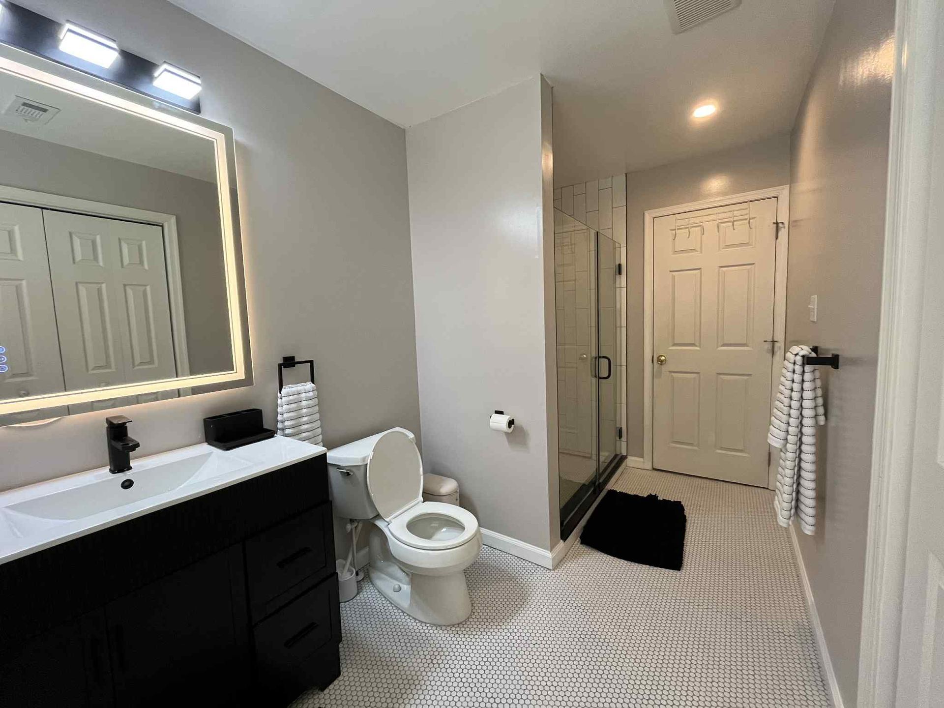 A bathroom with a toilet , sink and mirror.