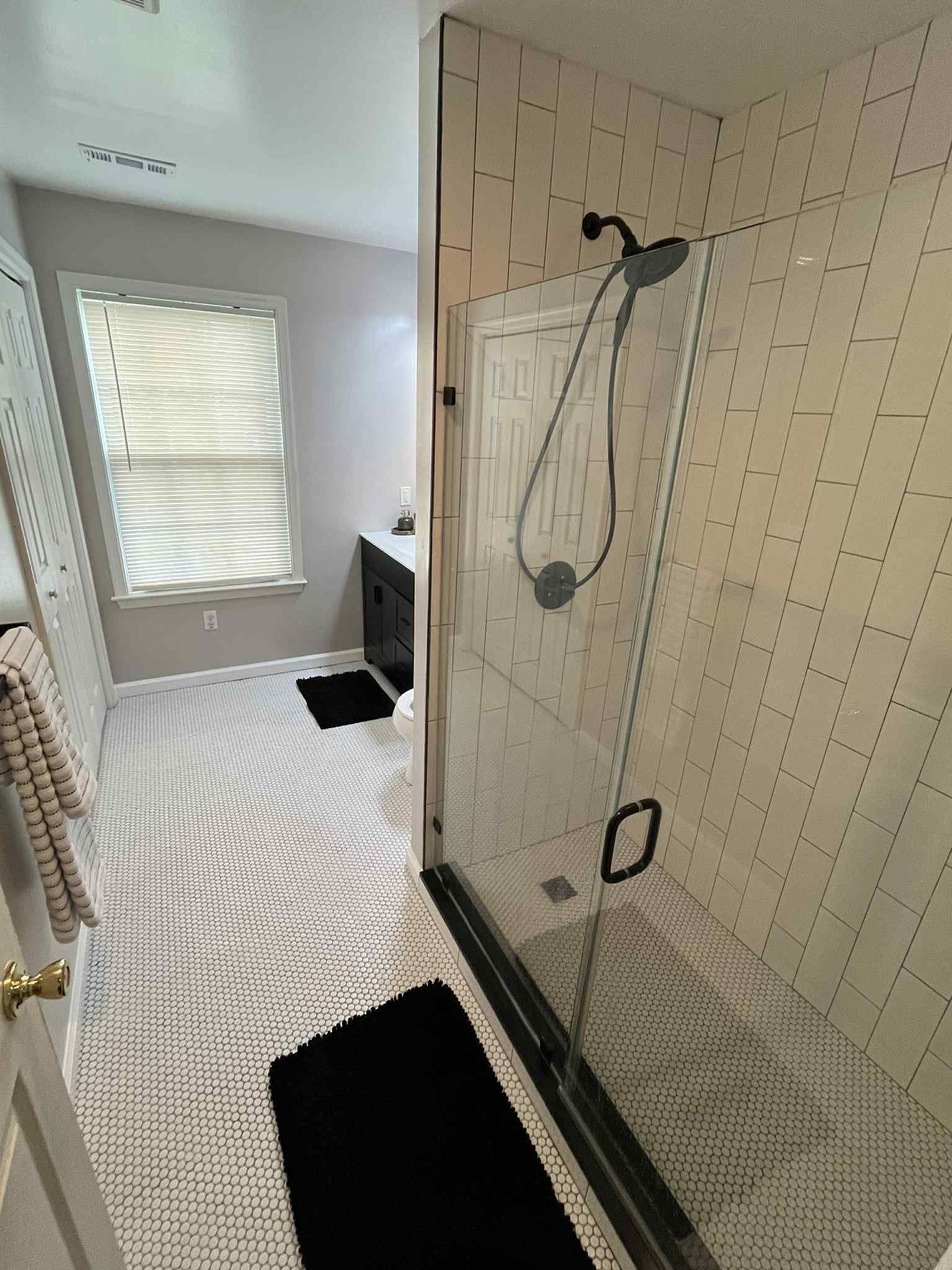A bathroom with a walk in shower and a window.