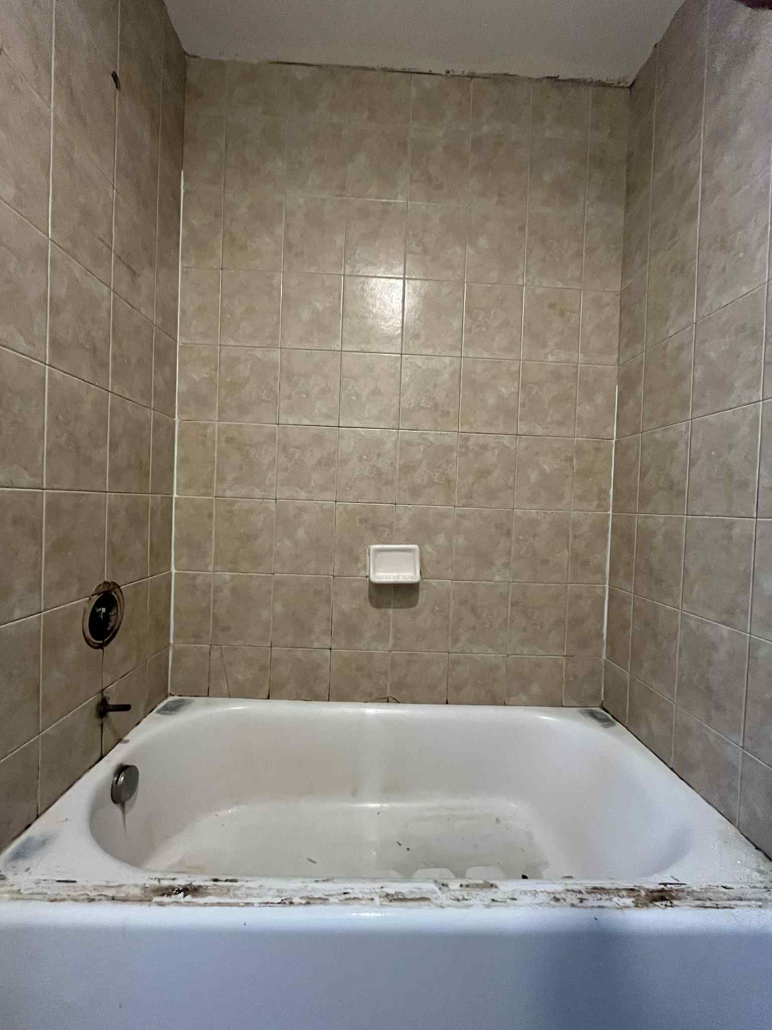 A bathtub in a bathroom with tiled walls.